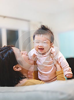 Happy Asian mother plays with baby holding girl in hands, baby smile, Family concept