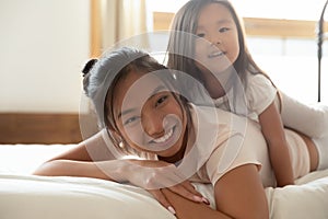 Happy Asian mother and small daughter cuddle in bed