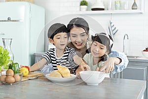 Happy Asian mother with son and daughter in kitchen. Enjoy family activity together