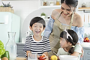 Happy Asian mother with son and daughter in kitchen. Enjoy family activity together