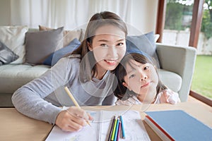 Happy asian mother teaching her cute kid daughter to studying