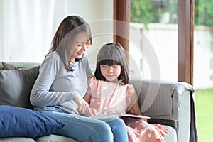 Happy asian mother teaching her cute kid daughter to studying at home