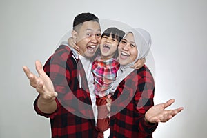 Happy Asian muslim family, father mother and baby girl daughter looking at camera and smiling with greeting gesture