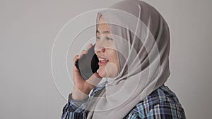 Happy Asian muslim woman wearing hijab talking on phone, good news conversation communication concept, smiling expression