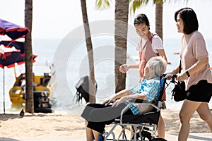 Happy asian old elderly with family walking long togetherness on the beach senior grandmother in a wheelchair smiling girl