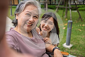 Happy Asian patients in a wheelchair use smartphones to take pictures with careful caregivers or nurse Concept of happy retirement