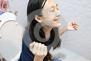 Happy asian people sitting on the toilet bowl,defecating or urinating in the bathroom,smiling child girl with relief and photo