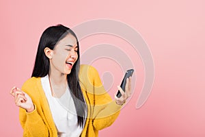 Happy Asian portrait beautiful cute young woman excited laughing holding mobile phone