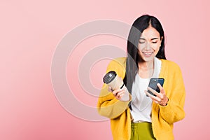 Happy Asian portrait beautiful cute young woman excited smiling holding mobile phone and coffee to go