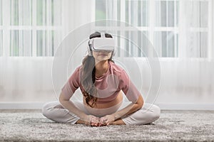 Happy Asian Pregnant woman using virtual reality glasses for practice yoga online class butterfly pose to meditation with big