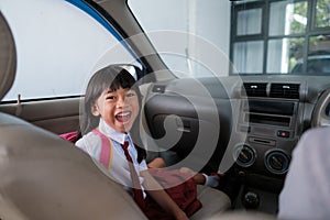 happy asian primary student while going to school by car