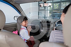 happy asian primary student while going to school by car
