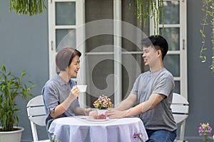 Happy asian retired mother with her adult son are relax talking together at front yard