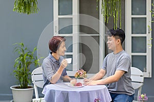 Happy asian retired mother with her adult son are relax talking together in morning at home.