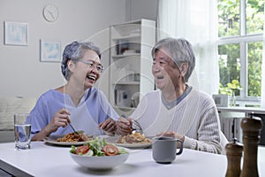Asian senior couple eating meal together in kitchen at home. Retirement senior couple lifestyle living concept