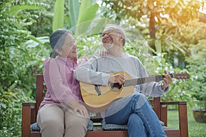 Asian senior couple elderly man playing guitar while his wife singing together