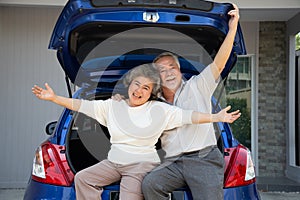 Happy Asian senior couple standing â€‹back of the car and enjoying journey trip.