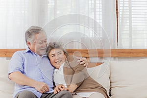 Happy Asian senior couple stay together on sofa at home in romantic moment. Retired lovely elderly smiling grandparent lover