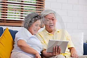 Happy Asian senior couple use tablet video chatting to family at home.aging at home concept