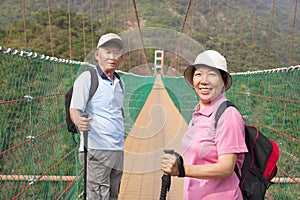 Happy asian senior couple walking on the bridge in