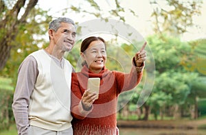 happy asian senior couple walking together in autumn park