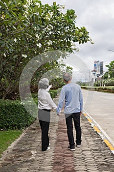 Happy Asian senior couple walking together on a tropical forest path Retired old man and woman having fun and enjoying outdoor