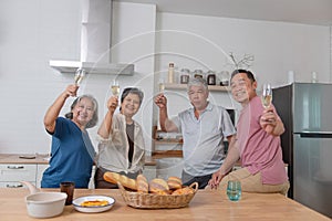 Happy Asian senior dining together drinking wine to celebrate