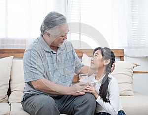 Happy asian senior elderly grandfather have grandchild look after and take care with giving milk and kiss on cheek while sitting