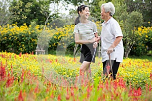 Happy asian senior grandmother and granddaughter walking in blooming garden,simple stress reduction,enjoying nature,smiling child