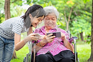 Happy asian senior grandmother and little child girl using cellphone together,playing video game on smart phone,smiling elderly