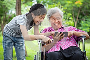 Happy asian senior grandmother and little child girl using cellphone together,playing video game on smart phone,smiling elderly