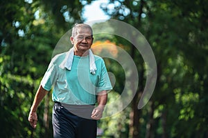 Happy asian senior man arm swing and jogging in autumn park. Concept of senior healthy lifestyle