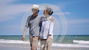 Senior man and woman couple holding hands walking from the beach sunny