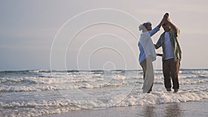 Happy Asian senior man and woman couple smile dancing resting relax on the beach