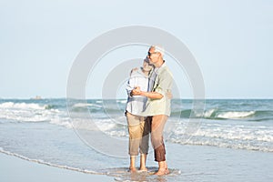 Happy Asian senior man and woman couple smile dancing resting relax on the beach