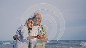 Happy Asian senior man and woman couple smile dancing resting relax on the beach