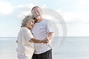 Happy asian senior retired couple dancing with relax smiling  on sea beach, elder man and woman enjoying with retired vacation.