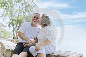 Happy asian senior retired couple, relax smiling elder man and woman enjoying with retired vacation at sea beach outdoor. Health