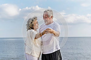 Happy asian senior retired couple relax smiling elder man and woman enjoying with retired vacation at sea beach outdoor. Health