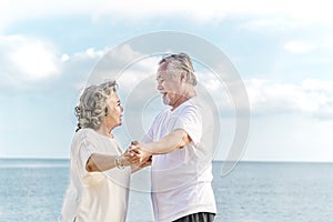 Happy asian senior retired couple, relax smiling elder man and woman enjoying with retired vacation at sea beach outdoor. Health