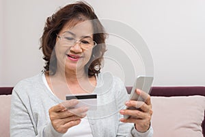 Happy Asian senior woman shopping online pay with credit card