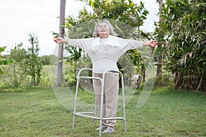 Happy asian senior woman standing with walker in garden at home . old health care lifesyle