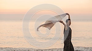 Happy Asian senior woman tun at beach with scarf fabric and copy space