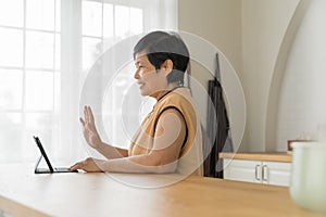 Happy Asian senior woman using looking at digital tablet computer