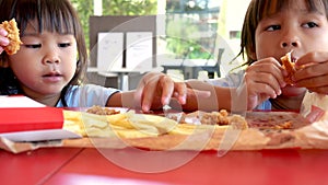 Happy Asian sibling sisters enjoy with eating fried chicken and French fries in service shop. Junk food and Health concepts.