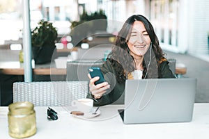 Happy asian smiling millennial girl looking at the screen of laptop