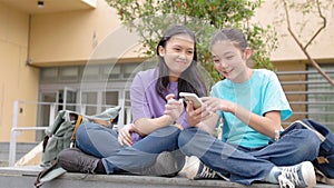 Happy Asian student girls using smart phone in school