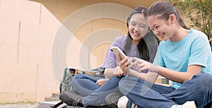 Happy Asian student girls using smart phone in school