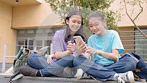 Happy Asian student girls using smart phone in school