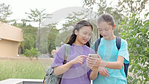 Happy Asian student girls walking and using smart phone in school